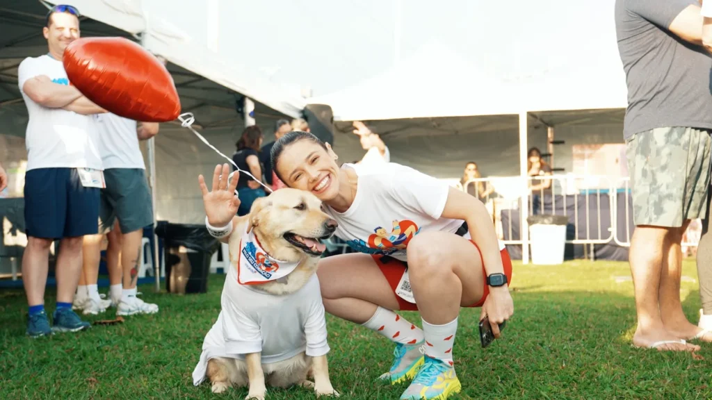 Participante sorridente com cão no evento MOVIMENTE-SE pelo seu coração da Unicardio, em Florianópolis